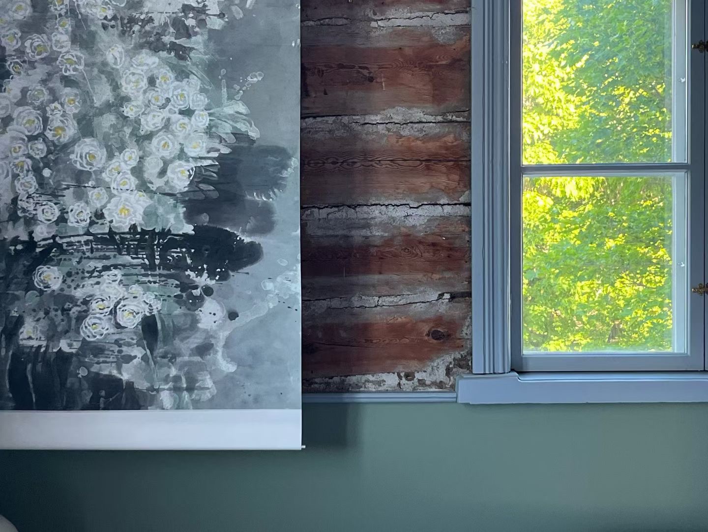 Botanical ink painting beside an aged timber wall and sunlit green leaves