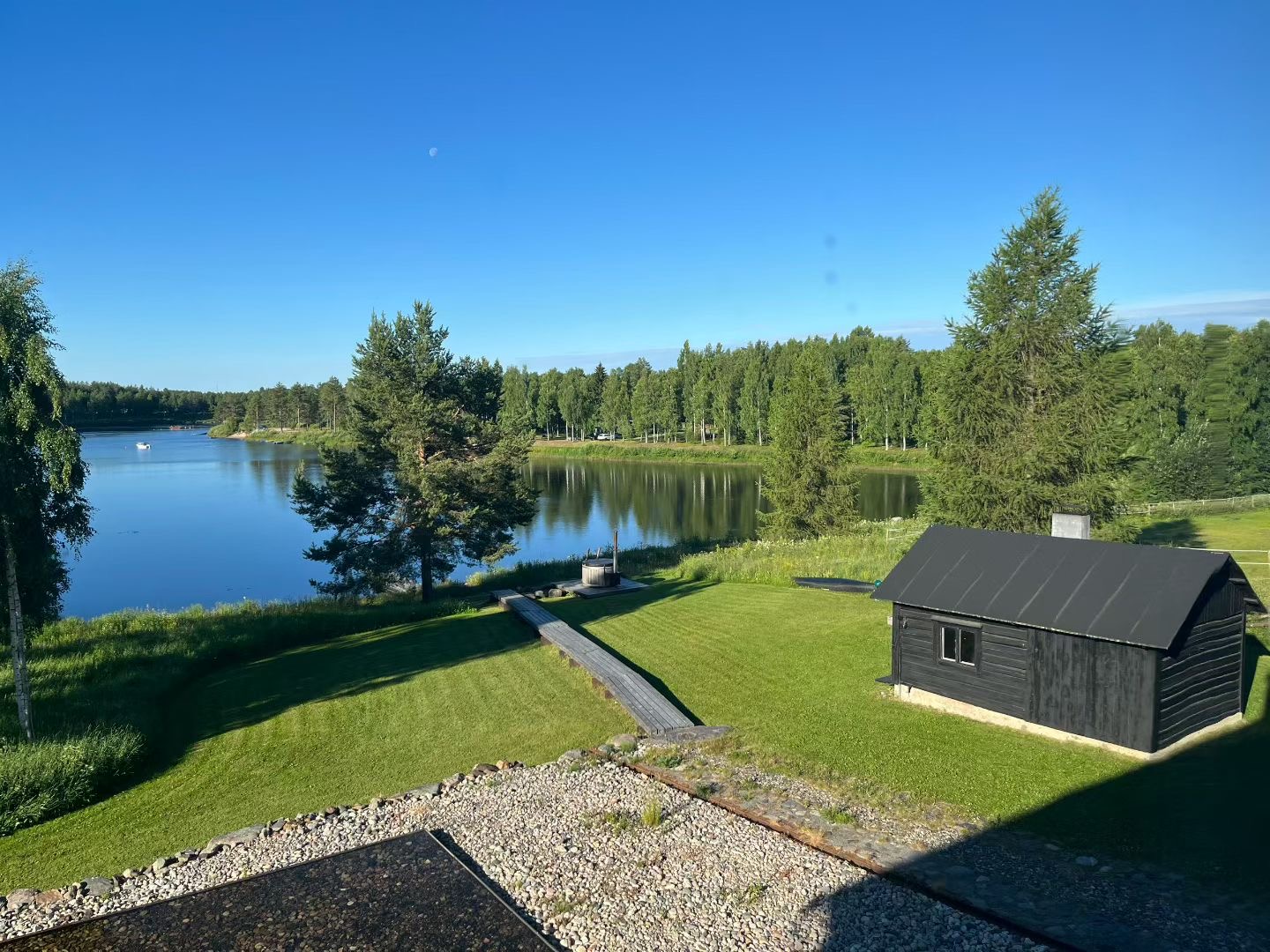 Nordic lake, green woodland and a dark timber cabin from the supplied landscape reference