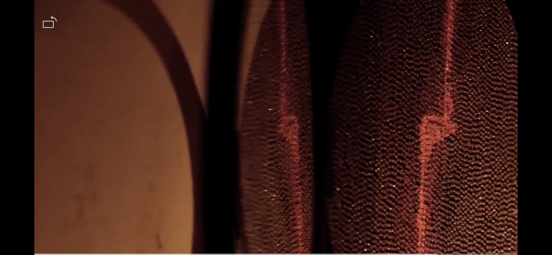Close-up of reddish woven fibres, texture and a stitched line
